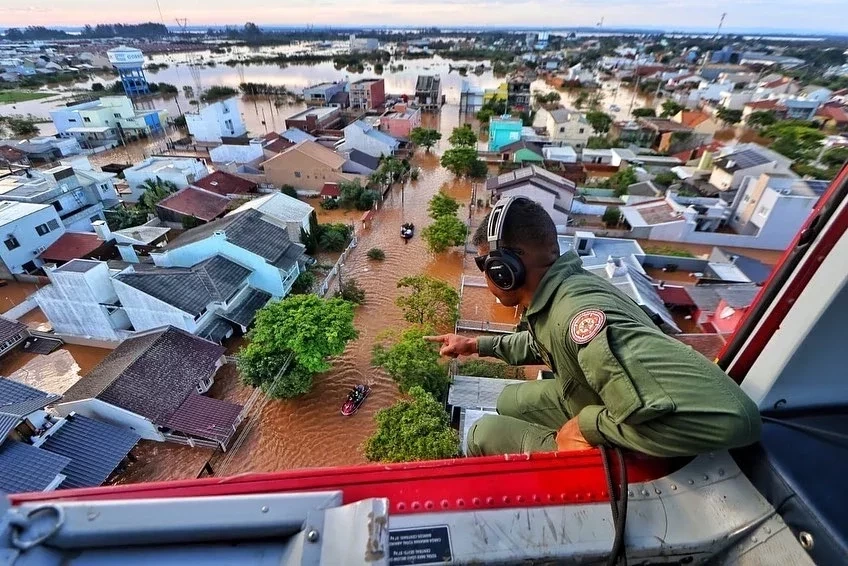 Bombeiro observa o cenário catastrófico no Rio Grande do Sul, em um helicóptero ele observa o resgate em um bairro totalmente alagado (Foto: Facebook/Governo do Rio Grande do Sul)