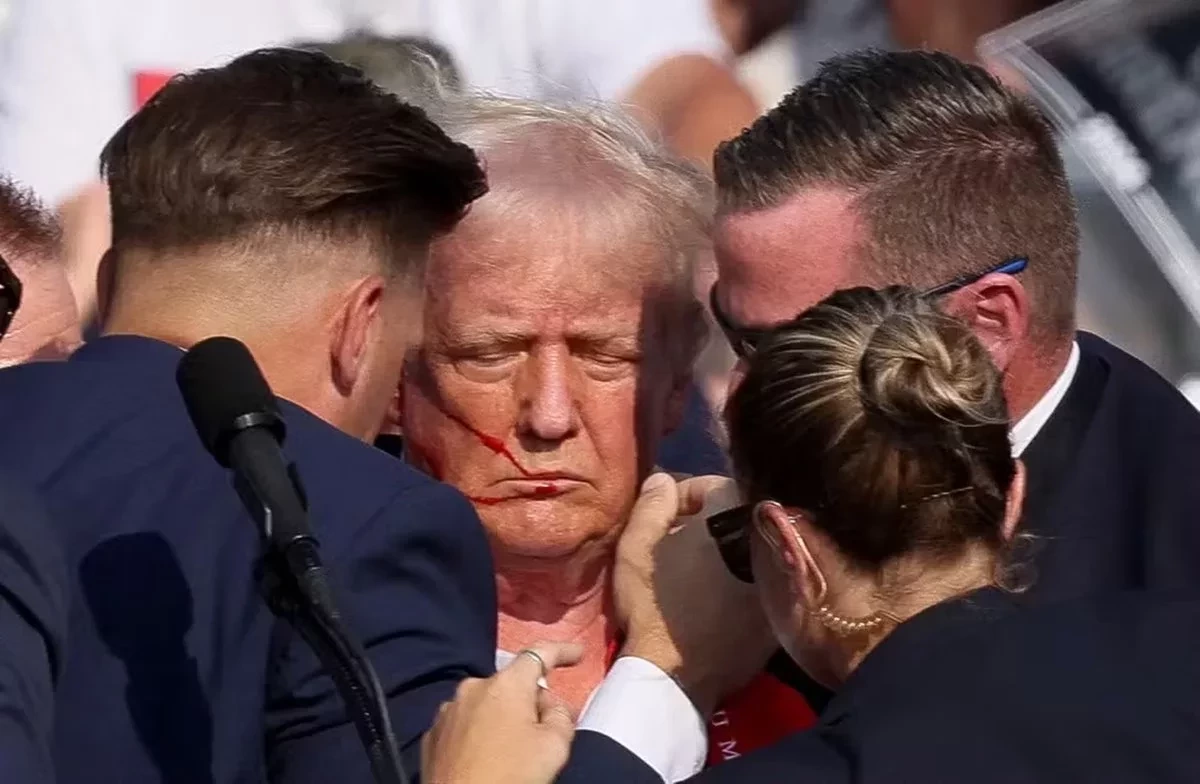 Donald Trump aparece com sangue no rosto e cercado por seguranças após tiros em comício — Foto: REUTERS/Brendan McDermid 